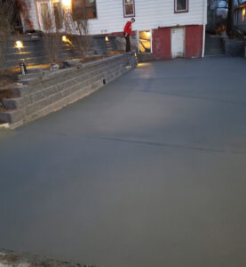 a concrete driveway or patio next to a house and two retaining walls
