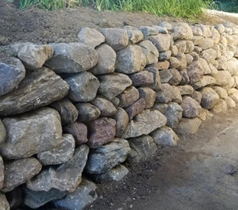 Professional natural stone retaining wall installation for a residential landscape in Des Moines.