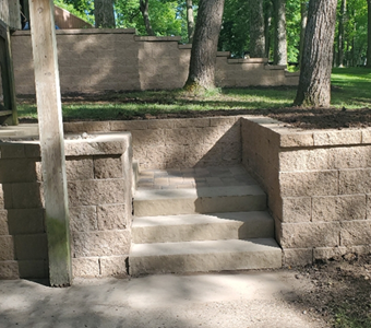 Custom concrete stairs integrated into a stone retaining wall for a seamless backyard transition in Des Moines.